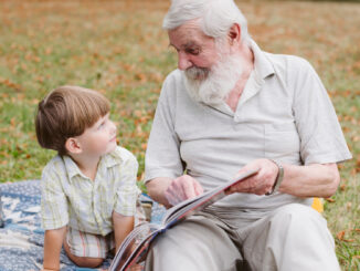 Dědeček s vnukem si čtou v parku.