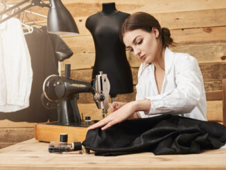 Žena šije na šicím stroji.