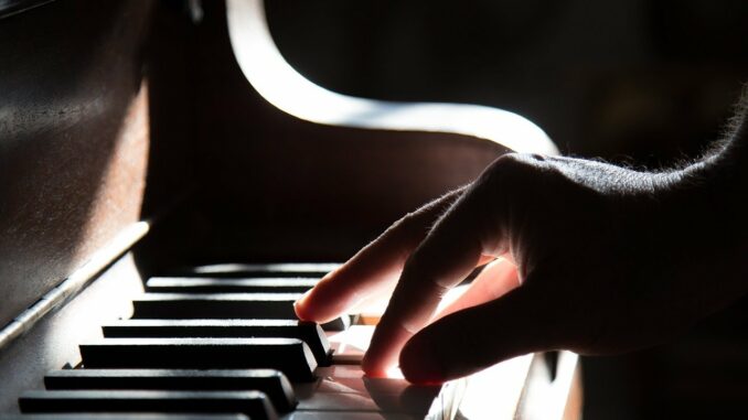 Detail ruky hrající na klavír.