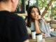 Zamyšlená žena sedí u kávy s mužem.